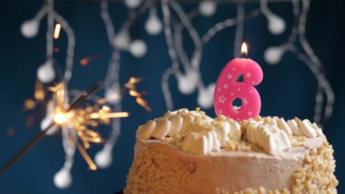 生日蛋糕，6号粉色蜡烛和蓝色背景上的烟火。慢动作和特写视图