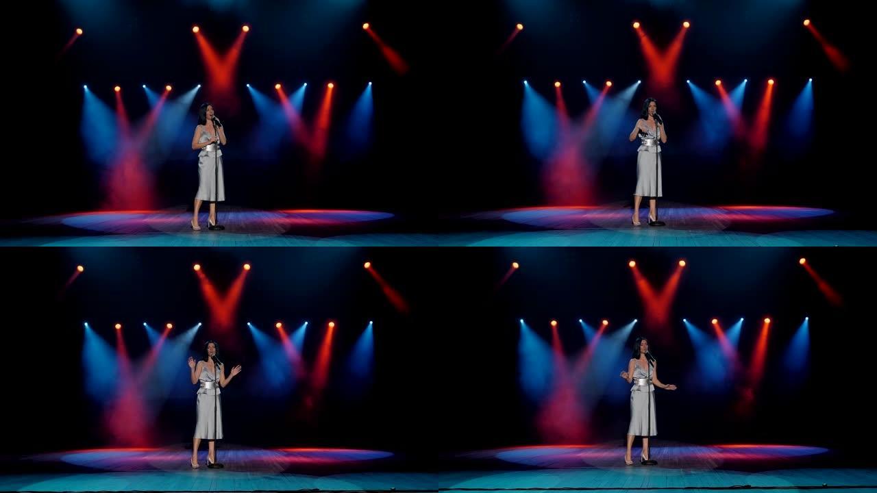 一位女歌手在舞台上用多色探照灯点亮的歌曲