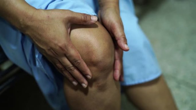 亚洲中年女性病人触摸和感觉疼痛她的膝盖: 健康的医学概念。