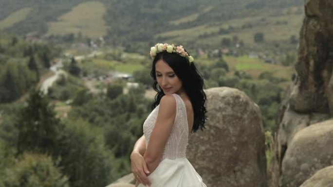 美丽可爱的新娘站在山上。恋爱中的女人