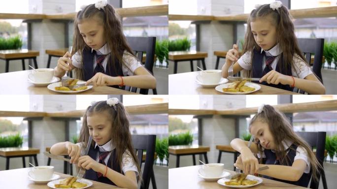 穿着校服的学生小学坐在学校食堂的桌子旁吃饭。