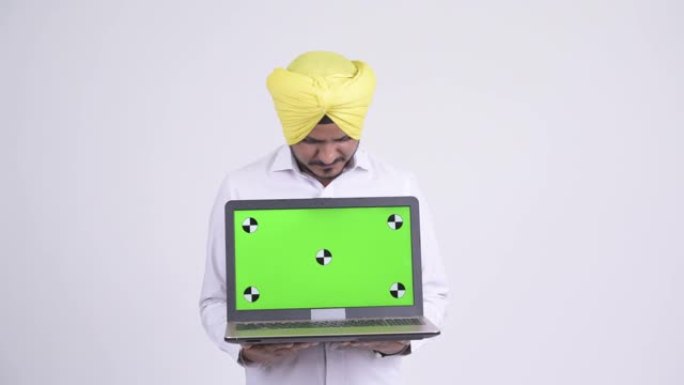 快乐的大胡子印度锡克教徒商人展示笔记本电脑