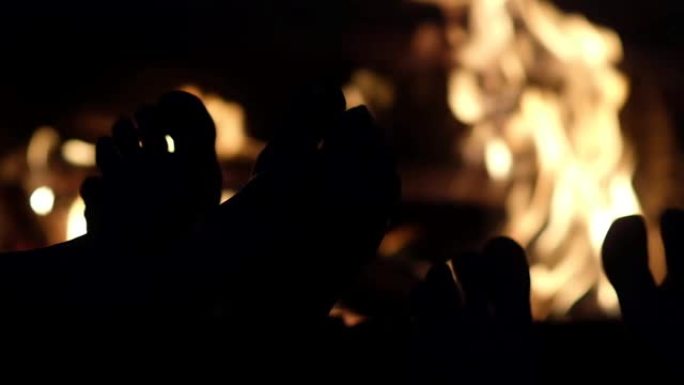赤裸的双脚在火旁的剪影特写。