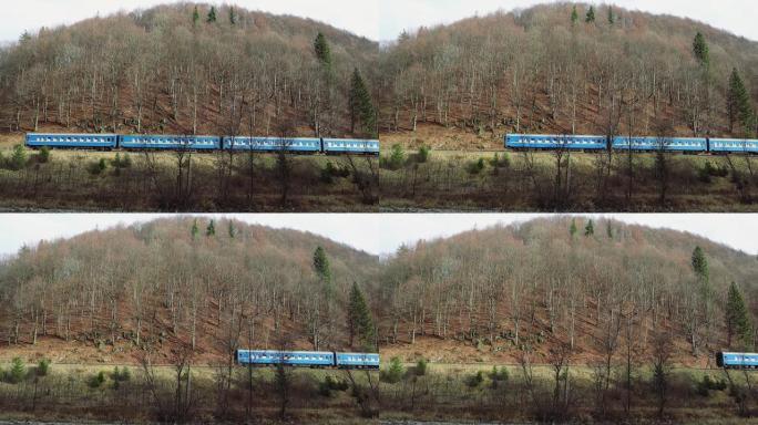 在大雾天的秋天，一列旧火车在铁轨上冒烟进入山上。旅客列车穿越森林