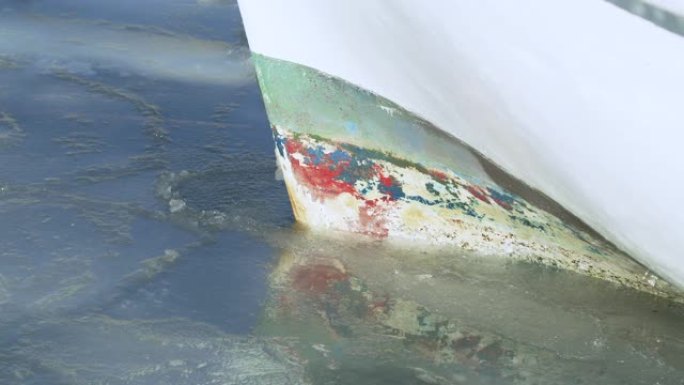 船体撞击冰盖的特写镜头。停泊的船等待冰融化。气候变化和极地气候。
