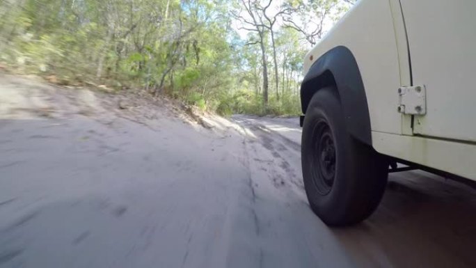 令人惊叹的稳定动作低角度镜头，一辆旧的四轮驱动越野车在澳大利亚昆士兰州沿海弗雷泽岛的内陆沙地上驶过森