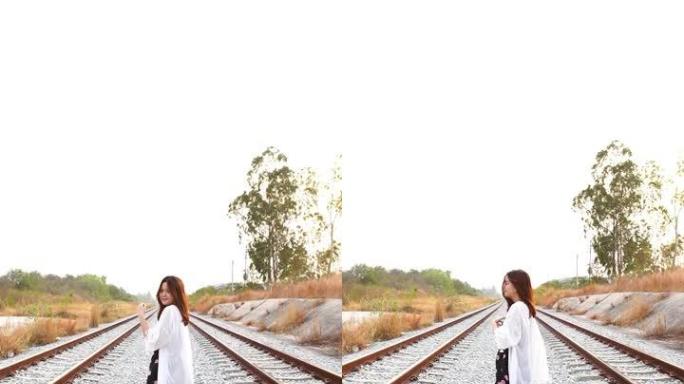年轻的亚洲旅游妇女独自走在铁轨上，极端地形场景，智能手机的垂直格式视频