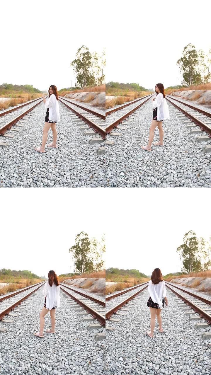 年轻的亚洲旅游妇女独自走在铁轨上，极端地形场景，智能手机的垂直格式视频