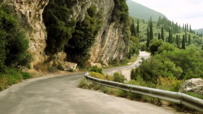 一辆红色小汽车在山区的乡间小路上行驶。希腊。4 k