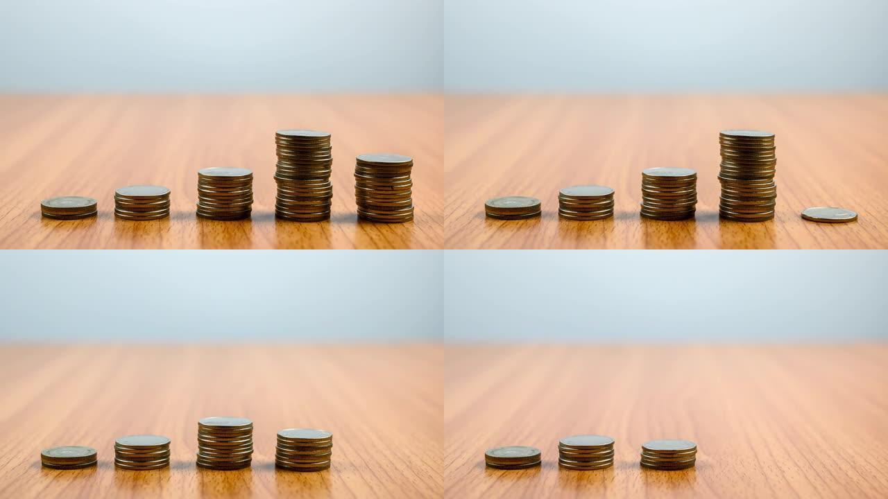 硬币减少列的4k停止运动。金币塔减少，失去投资和利润的概念背景。硬币堆在木头桌子上。