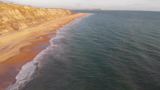 空中前锋揭示了Hengistbury Head悬崖的镜头，美丽的沙滩和湛蓝的海水在雄伟的蓝天白云下