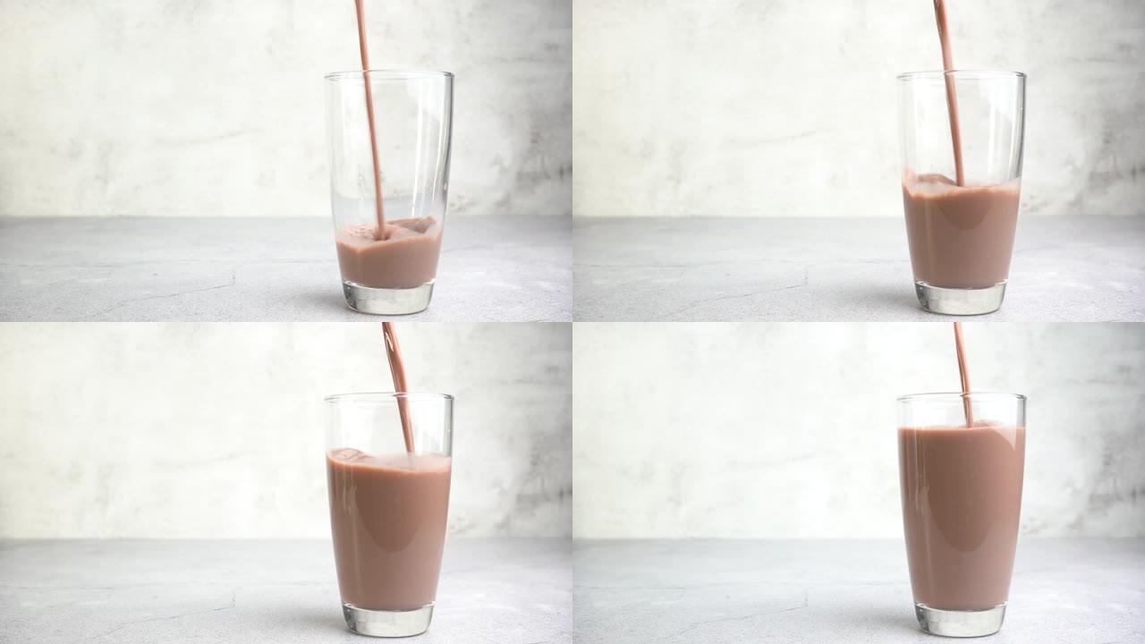 关闭将巧克力牛奶倒入桌子上的玻璃杯中。