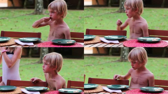 孩子在户外吃饼干，坦率英俊的金发小男孩吃甜
