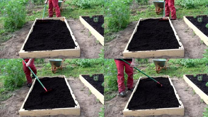 园丁在新的木制高架床上耙黑土腐殖质