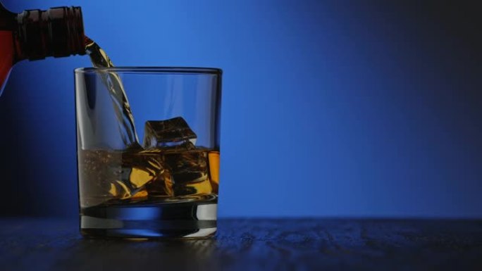 酒精从瓶子里倒入玻璃中。带复制空间的饮料概念。