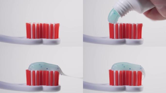 从白色的管子上，一个男人将蓝色的牙膏挤到塑料牙刷的红色刷毛上