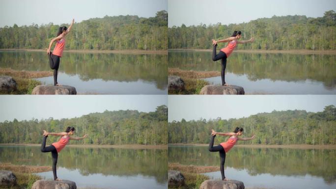 4k慢，亚洲年轻迷人的女人正在湖边练习瑜伽。放松并集中在大自然中。