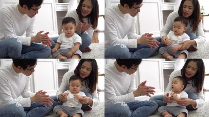 快乐的亚洲三口之家，年轻的父亲和母亲在家里与男婴孩子玩游戏拍手，父母享受家庭时光