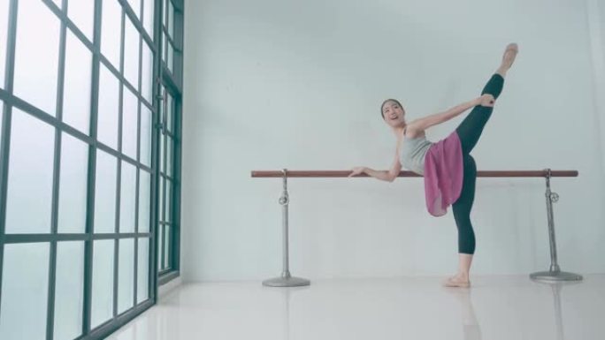 泰国芭蕾舞演员在教室里伸展。经过长时间的训练，她正在做最后的练习。