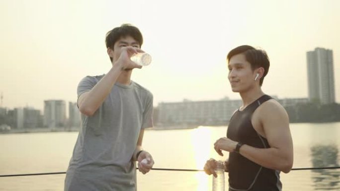 快乐的男人和朋友一起在户外锻炼时喝水和休息
