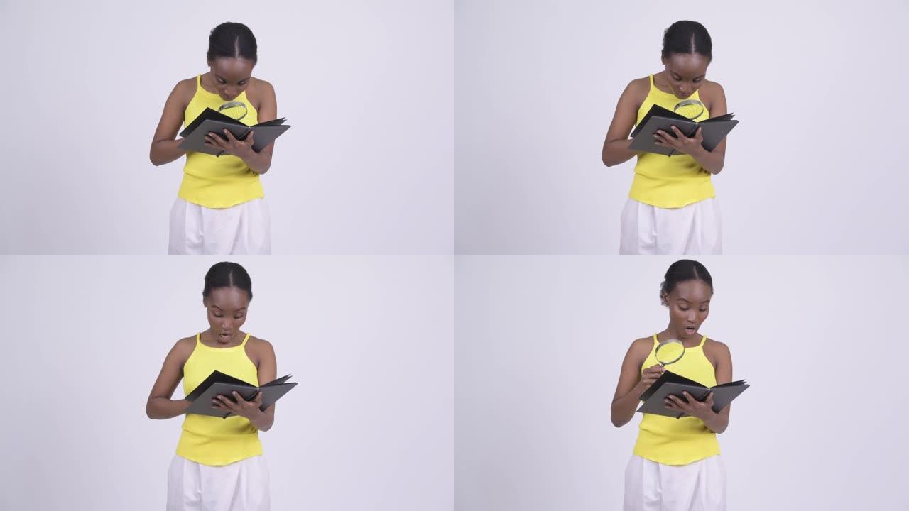 年轻美丽的非洲女人阅读放大镜