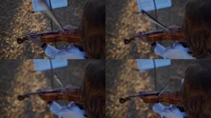 一个小男孩在公园里拉小提琴的高角度观看视频