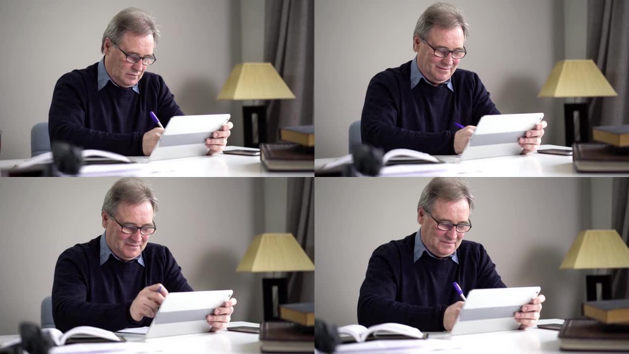 使用平板电脑和书写眼镜的白人老人肖像。认真自信的退休人员坐在室内的桌子旁上网。退休、休闲、生活方式、