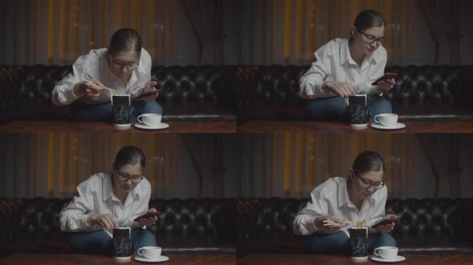 30多岁戴眼镜的女人用筷子吃亚洲盒饭看着笔记本电脑显示器。深夜孤独的家庭晚餐与小玩意。
