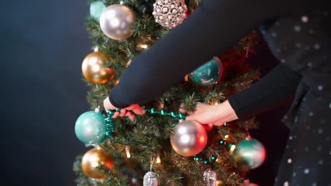 女人的手的特写镜头在圣诞树上放了一个花环。