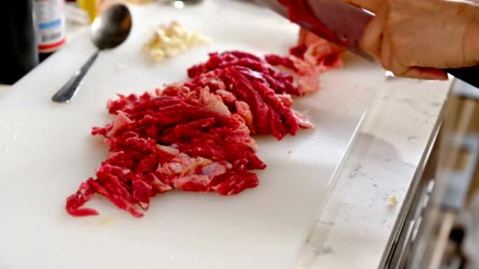 厨师在塑料屠夫上用刀将生牛肉切成薄片