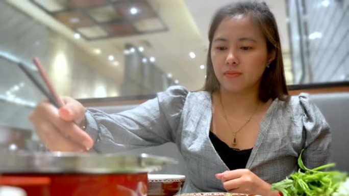 场景慢动作年轻美丽的亚洲女人在餐厅吃sha烧烧火锅，周末假期的概念，亚洲女人的生活方式