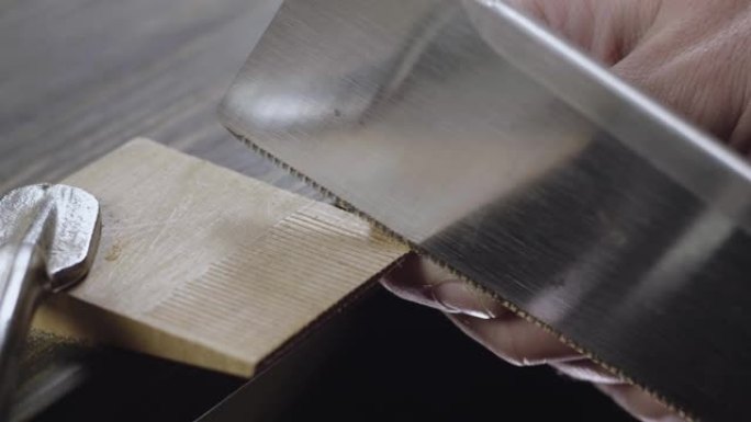 用手锯锯木制细节的人的手的特写。木匠制作手工木梳。电影4k视频