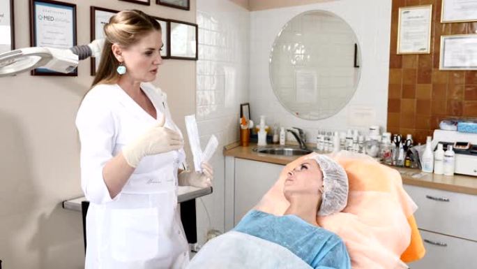医疗诊所的美容师与一位女性客户交谈，解释面部手术的细节并展示无菌治疗工具