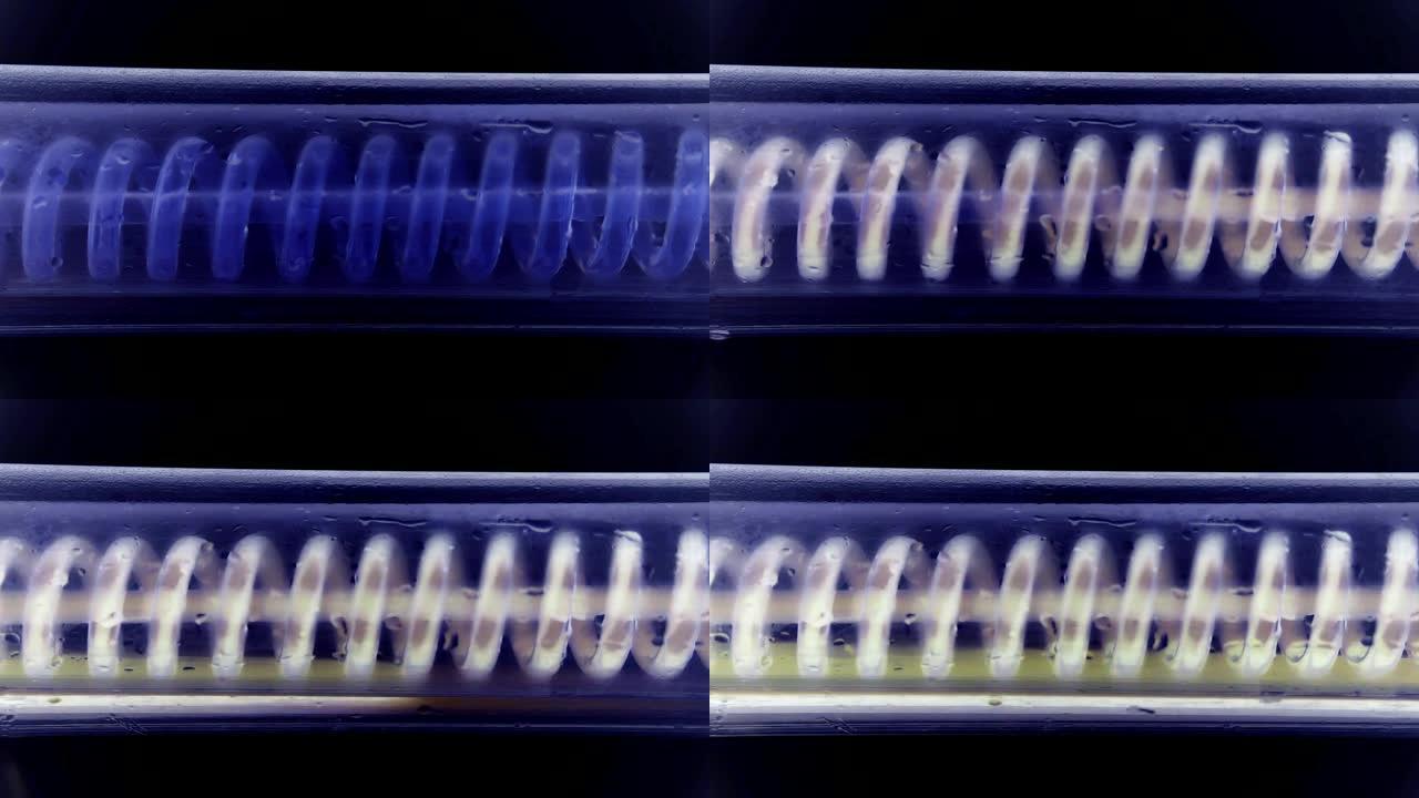 液体流动，从左到右水平盘旋。科学实验室冷凝器，特写。科学实验室实验中的流体。彩色化学品通过冷凝器或玻
