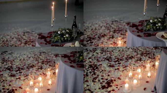 在体育场溜冰场中间，一张浪漫晚餐的桌子上装饰着蜡烛和玫瑰花瓣。