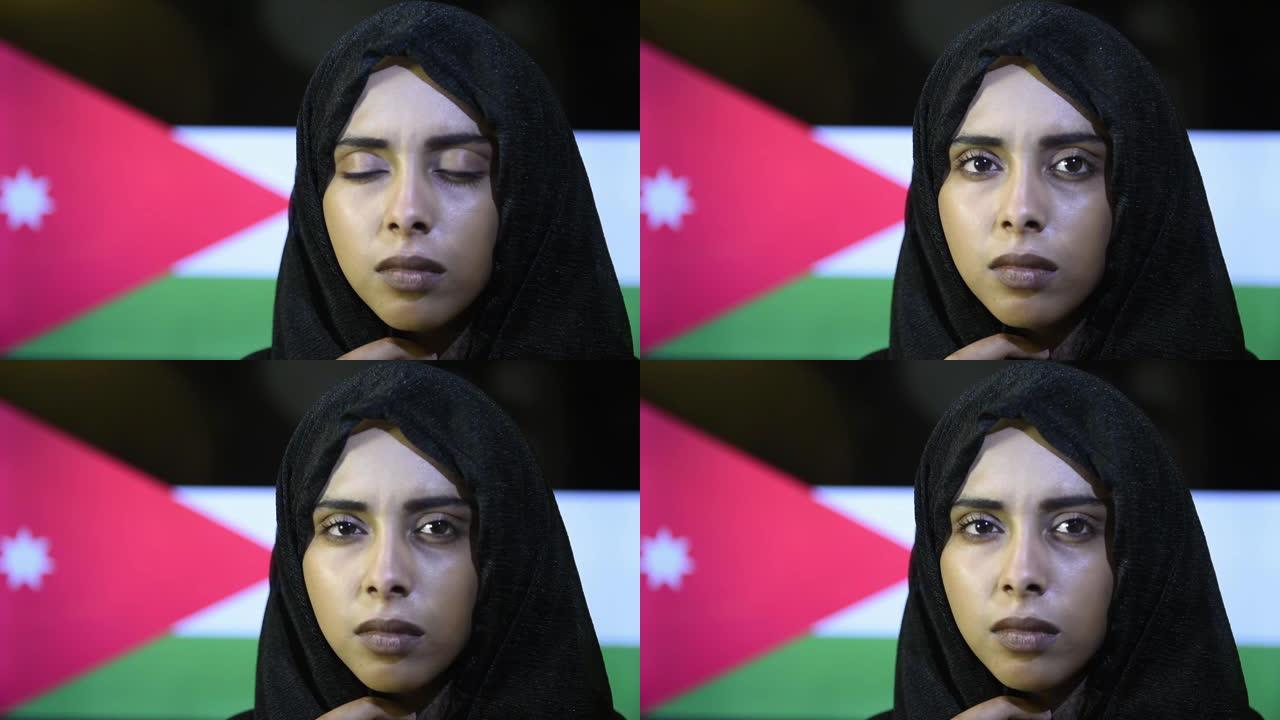 戴着头巾的年轻美丽的穆斯林女孩的特写肖像，站在约旦国旗上