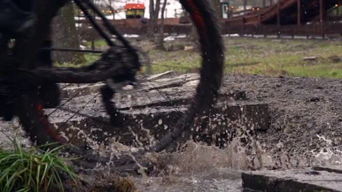 在土路上骑自行车。慢动作从自行车车轮上溅水。