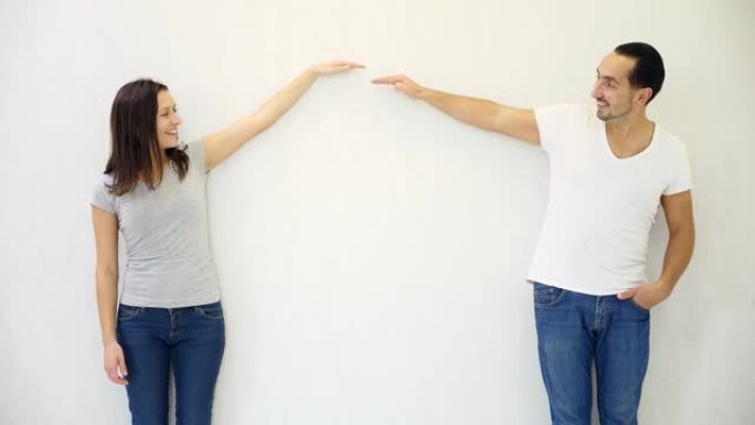黑发男人和女人站在白色墙壁背景下，举手，展现成长和成功。