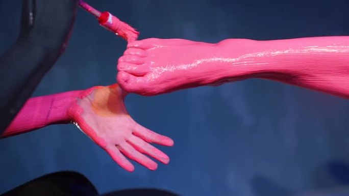 特写，艺术家用粉红色油漆画模型腿。