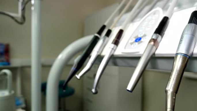 牙科诊所: 控制台上有牙科医疗设备的房间。将黑色手套放在牙科仪表板上的移动钻头组。特写。牙科护理工具