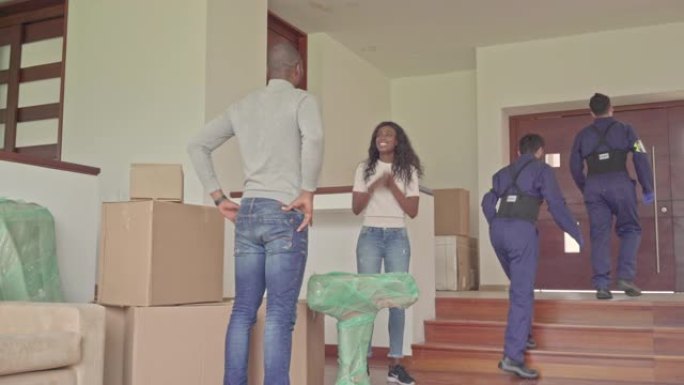 黑发拉丁夫妇感谢一家搬家公司的工人，他们帮助他们拿箱子