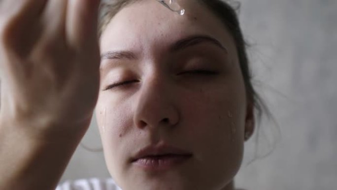 美容和个人护理-一个健康的女人用移液管将血清涂在脸上。天然成分的天然化妆品
