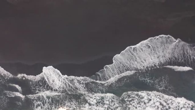 鸟瞰图。黑沙滩。美丽的海浪撞击海岸线。加那利群岛特内里费岛的天然火山海滩
