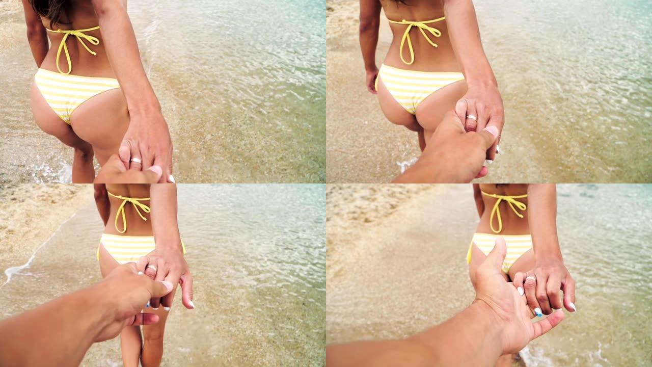 一个男孩和一个女孩牵着手，在沙滩上沿着大海散步。慢动作