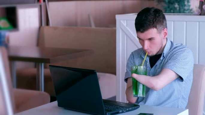 残疾人自由职业者残肢手在咖啡馆用笔记本电脑工作，喝着鸡尾酒。