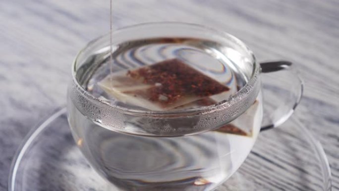 一袋红茶滴落并漂浮在玻璃透明杯子中