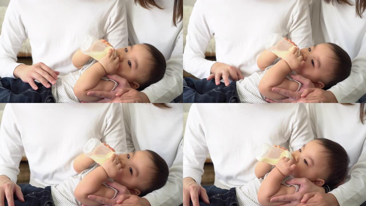 亚洲家庭的年轻父母在家中用奶瓶喂养男婴