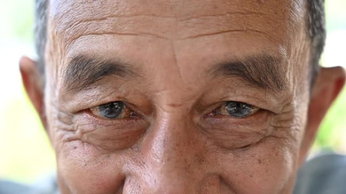 老年人闭上眼睛，沉思的亚洲老人慢动作。一个成年人看着镜头想了些什么。亚洲男子特写概念背景慢动作。