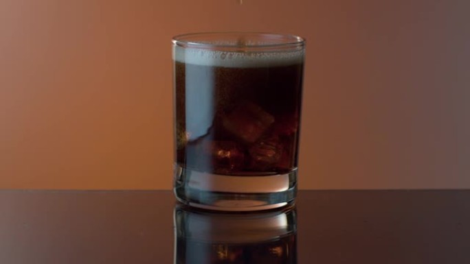 可乐倒入威士忌和冰的玻璃杯中