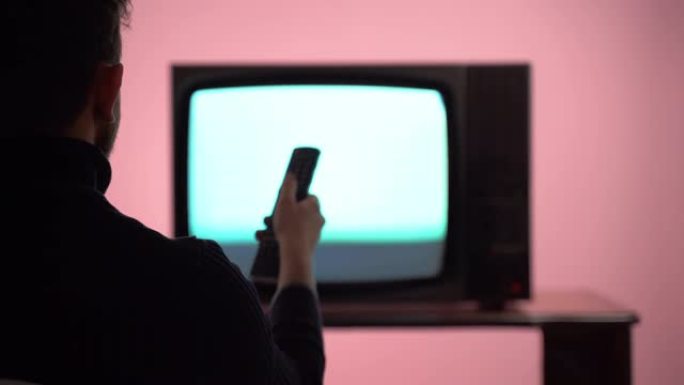 屏幕上有噪音干扰的老式电视。男性手持电视遥控器和换频道。老式电视和广播，复古风格